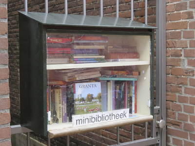 908175 Afbeelding van een minibibliotheek opgehangen aan een toegangshek naast het pand Pauwstraat 24 te Utrecht.